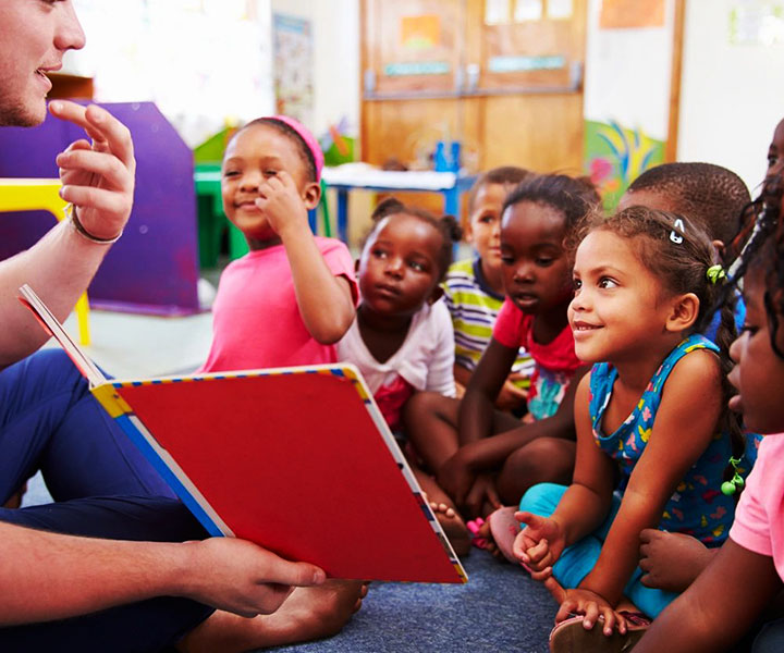 A person teaching kids with holding book in hand